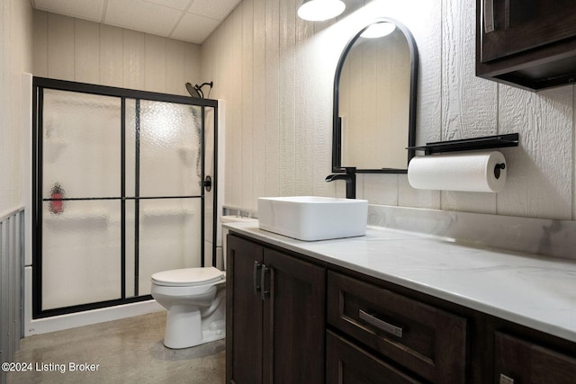 bathroom featuring vanity, wooden walls, toilet, and walk in shower