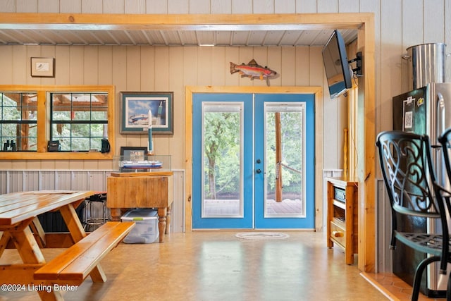 interior space featuring french doors, beam ceiling, and wood walls