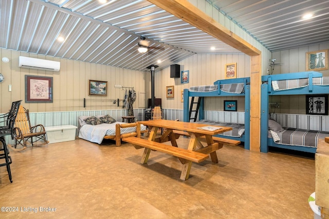 interior space with concrete flooring, an AC wall unit, a wood stove, and lofted ceiling