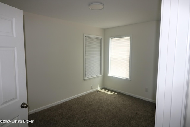 spare room with dark carpet