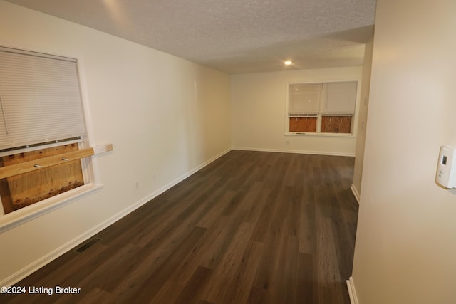 unfurnished room with dark hardwood / wood-style flooring and a textured ceiling