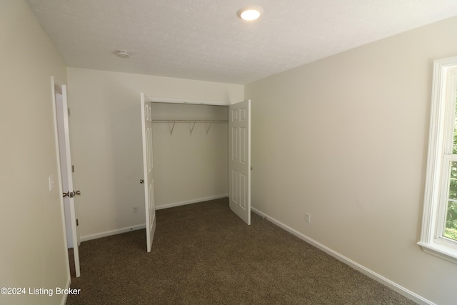 unfurnished bedroom with a closet and dark colored carpet