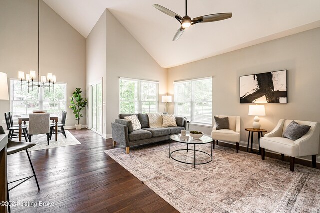 living area with high vaulted ceiling, dark wood-style flooring, baseboards, and ceiling fan with notable chandelier