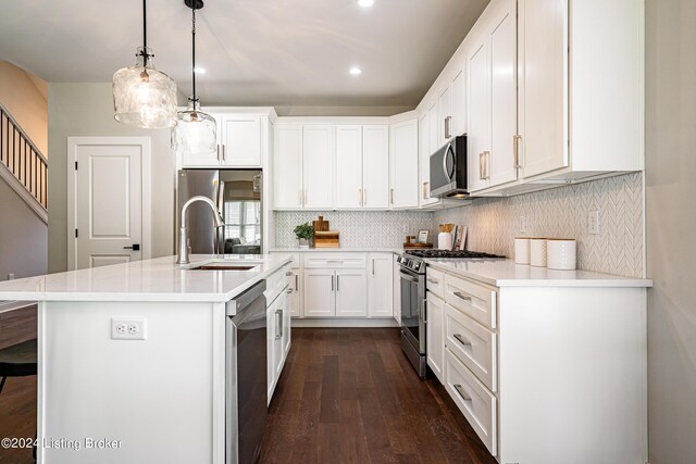 kitchen with appliances with stainless steel finishes, decorative backsplash, a sink, and white cabinets