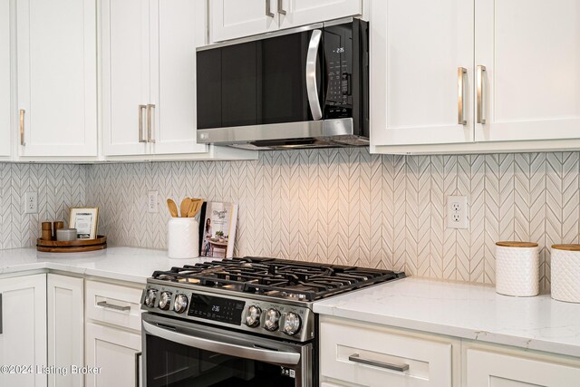 kitchen with stainless steel appliances, white cabinetry, decorative backsplash, and light stone countertops