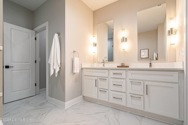 bathroom featuring marble finish floor, a sink, baseboards, and double vanity