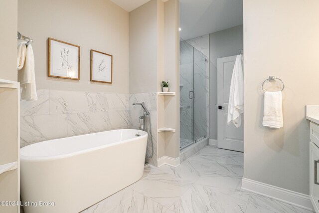 full bath featuring vanity, baseboards, marble finish floor, a soaking tub, and a marble finish shower