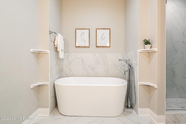 full bath featuring marble finish floor, tile walls, a freestanding bath, and tiled shower