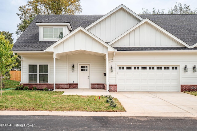 view of front of house featuring an attached garage, a shingled roof, concrete driveway, and brick siding