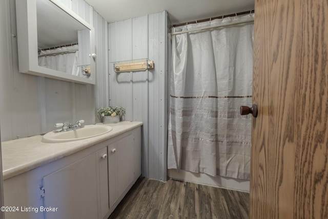 bathroom with wood walls, wood-type flooring, vanity, and a shower with shower curtain