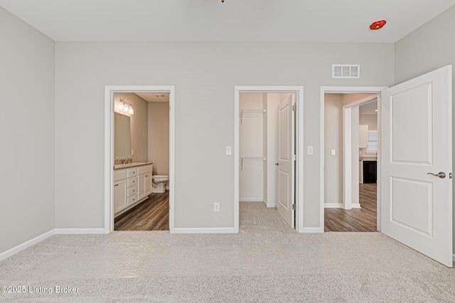 unfurnished bedroom featuring sink, connected bathroom, carpet floors, a spacious closet, and a closet