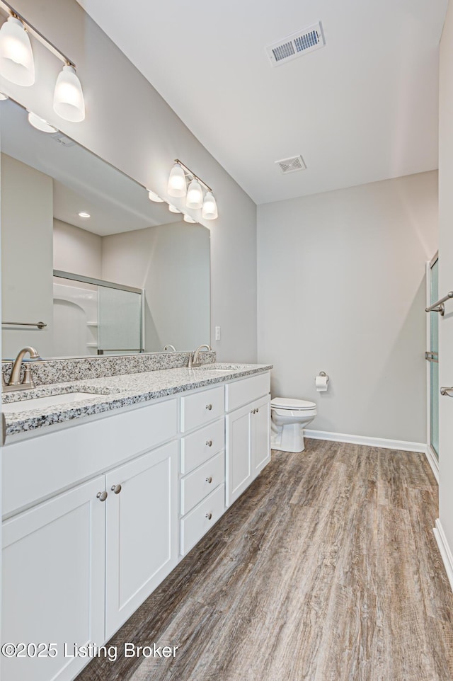 bathroom with vanity, toilet, a shower with shower door, and hardwood / wood-style floors