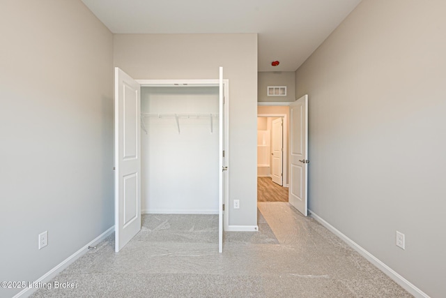 unfurnished bedroom with light colored carpet and a closet