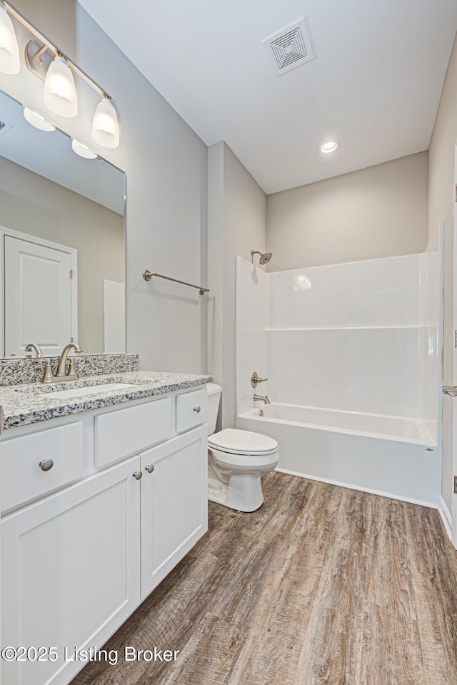 full bathroom featuring vanity, hardwood / wood-style flooring, shower / washtub combination, and toilet