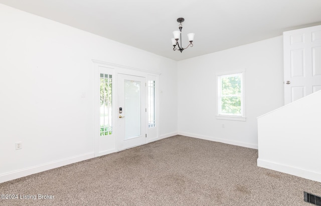 carpeted spare room with a chandelier