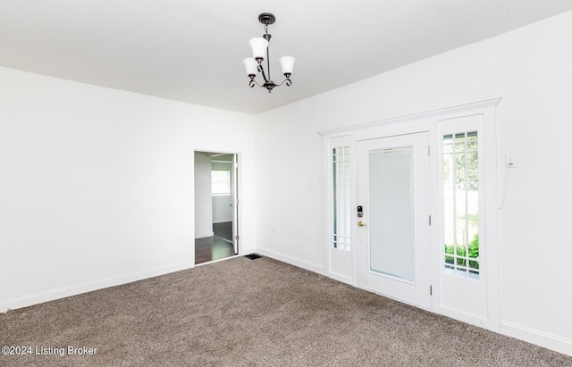 spare room featuring a notable chandelier and carpet flooring