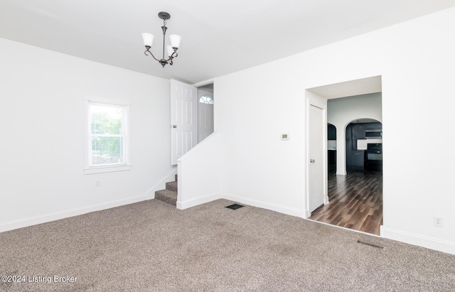 carpeted empty room featuring an inviting chandelier