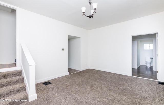 carpeted spare room featuring a notable chandelier