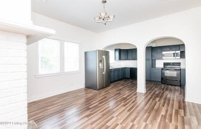 kitchen with stainless steel appliances, pendant lighting, a chandelier, and dark hardwood / wood-style flooring