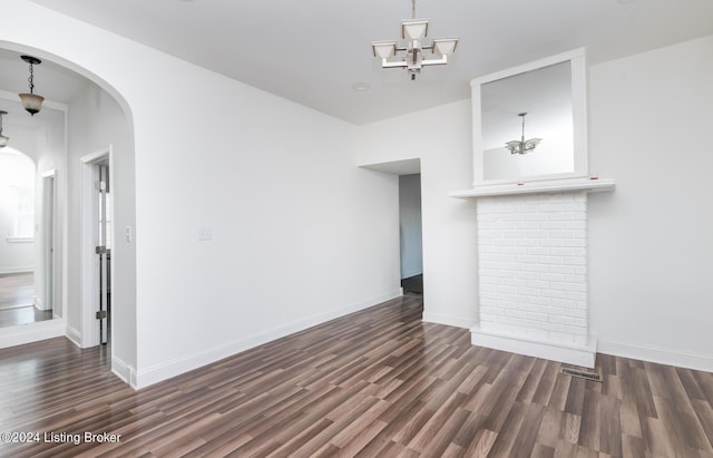 unfurnished living room featuring an inviting chandelier and dark hardwood / wood-style floors