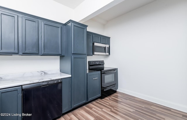 kitchen featuring blue cabinets, beamed ceiling, light wood-type flooring, light stone countertops, and black appliances