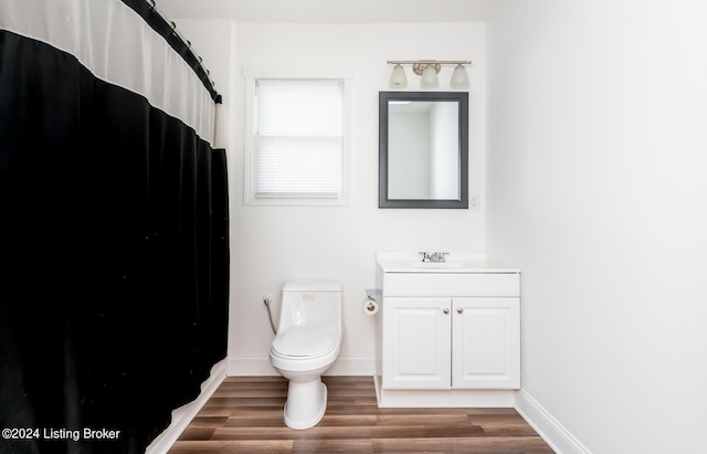 bathroom with toilet, vanity, and hardwood / wood-style floors