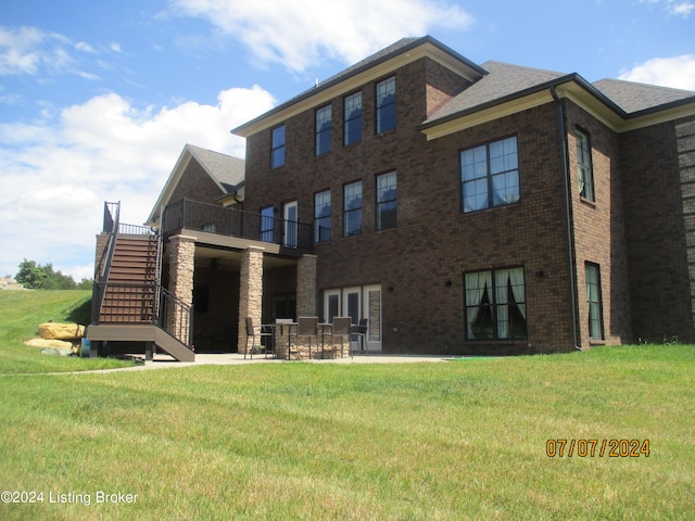 rear view of property with a balcony, a lawn, and a patio