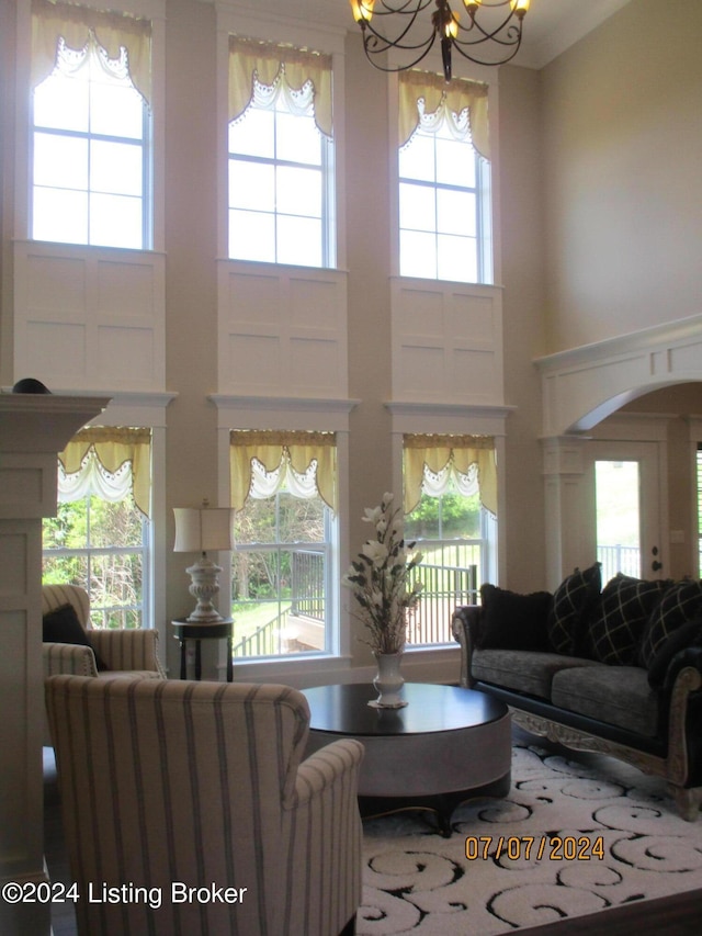 living room with a high ceiling, a chandelier, and a healthy amount of sunlight