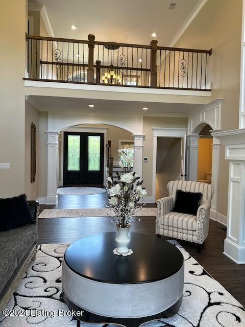 living room with hardwood / wood-style flooring, a high ceiling, crown molding, and decorative columns