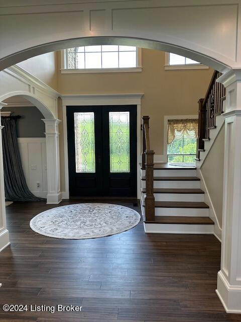 entryway featuring a towering ceiling, a wealth of natural light, dark hardwood / wood-style floors, and french doors