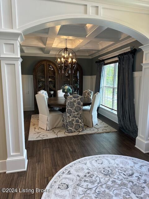 dining area with dark wood-type flooring, crown molding, coffered ceiling, and a notable chandelier