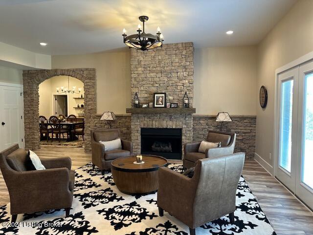 living room with an inviting chandelier, hardwood / wood-style flooring, and a brick fireplace