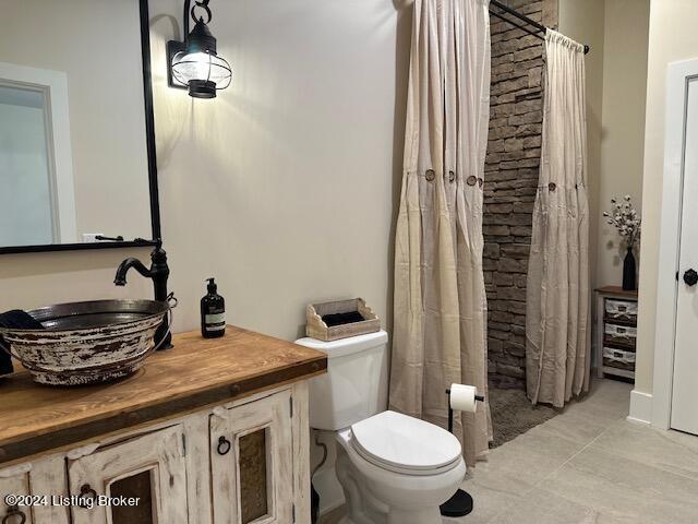 bathroom with toilet, vanity, tile patterned floors, and curtained shower