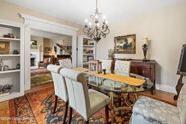 dining area featuring dark wood-type flooring, built in features, and a chandelier