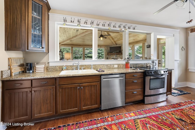 kitchen featuring sink, ceiling fan, stainless steel appliances, light stone counters, and dark hardwood / wood-style flooring