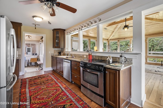 kitchen with light stone counters, sink, dark hardwood / wood-style flooring, and stainless steel appliances