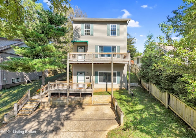 back of house featuring a balcony, a lawn, and a wooden deck