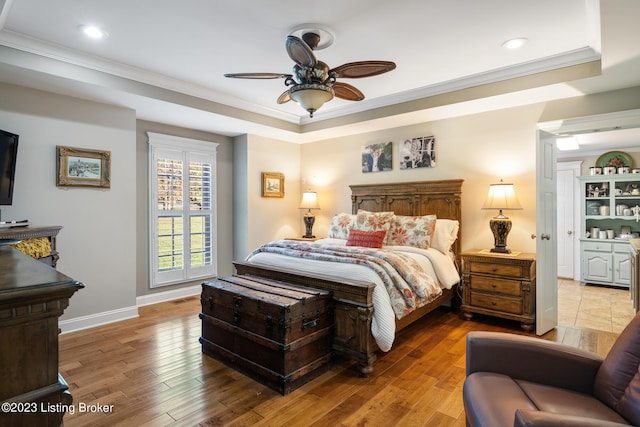 bedroom with hardwood / wood-style flooring, crown molding, ceiling fan, and a tray ceiling