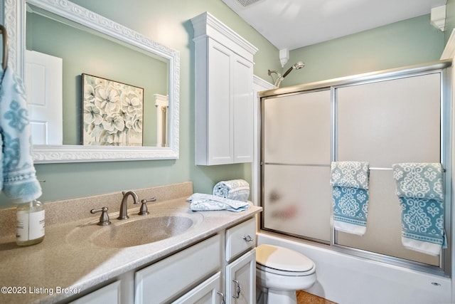 full bathroom featuring enclosed tub / shower combo, vanity, and toilet