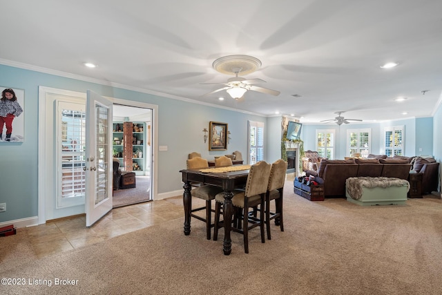 carpeted dining room with french doors, ceiling fan, ornamental molding, and a fireplace