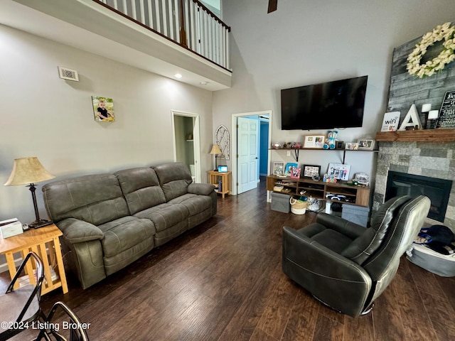 living room featuring a stone fireplace, hardwood / wood-style floors, and a high ceiling