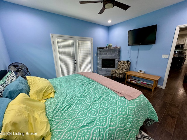 bedroom with ceiling fan, hardwood / wood-style flooring, a stone fireplace, and a closet