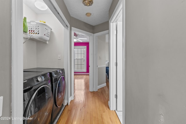 laundry area featuring a textured ceiling, washer and dryer, and light wood-type flooring