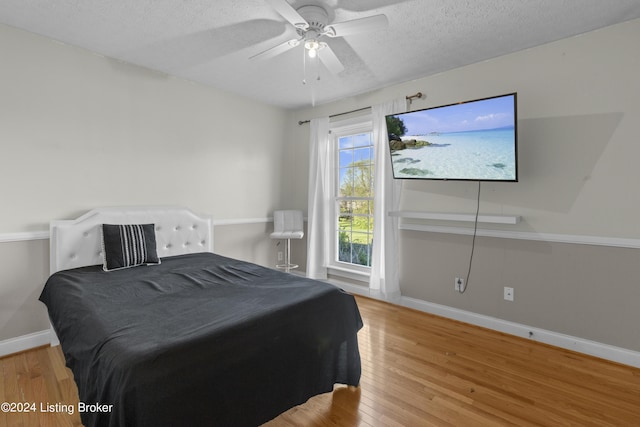 bedroom featuring hardwood / wood-style flooring, ceiling fan, and a textured ceiling