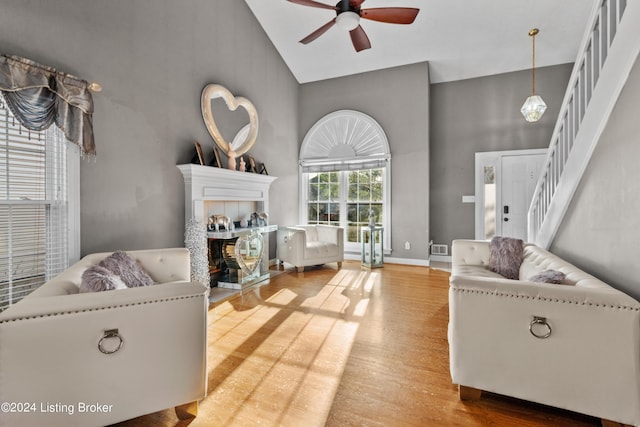 living room with ceiling fan, high vaulted ceiling, and a tile fireplace