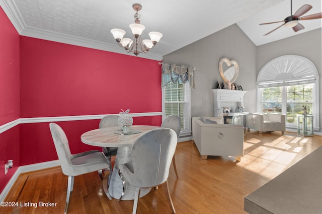 dining space featuring crown molding, ceiling fan with notable chandelier, vaulted ceiling, and light wood-type flooring