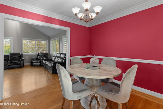 dining space with crown molding, a chandelier, vaulted ceiling, and hardwood / wood-style floors