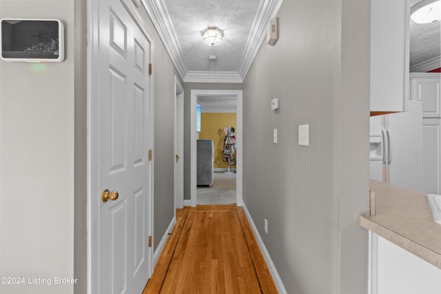 corridor featuring ornamental molding, light hardwood / wood-style floors, and a textured ceiling