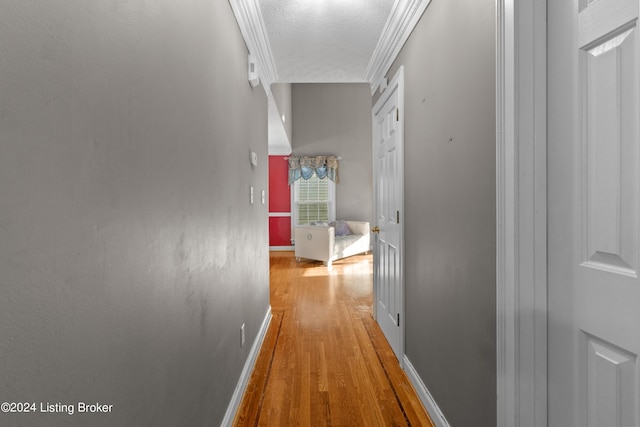 corridor featuring crown molding, a textured ceiling, and hardwood / wood-style flooring