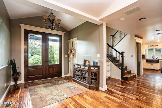 entrance foyer featuring vaulted ceiling, wood-type flooring, a chandelier, and french doors